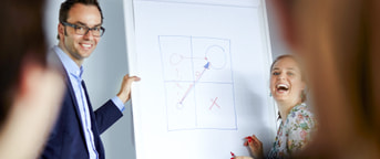 Lachende Mitarbeitende vor Flipchart Deux collaborateurs souriants devant un tableau à feuillles